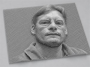 A polished chrome cylinder grid rises and falls into a striking relief portrait, turning contrast into sculpted height. From a north east isometric view, the face, glasses, hair, jaw, and shoulders emerge with metallic precision. Reflective domes, tight spacing, and clean lighting create a futuristic display of dimensional portrait art.