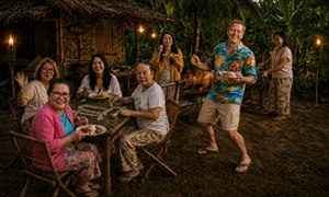 A joyful tropical evening gathering unfolds beside a rustic bamboo hut, where friends share food, laughter, and mahjong beneath glowing tiki torches. A golden lechon turns over open coals while a smiling host tends the spit. Palm foliage, warm firelight, and lively expressions create an inviting Filipino celebration of friendship.
