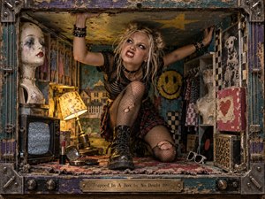 A defiant young woman crouches inside a cramped, distressed shadow-box room, pushing against its low ceiling amid mannequins, dolls, a static-filled television, vintage decor, and suburban imagery. Acidic teal, yellow, red, and charcoal tones glow under harsh directional light, while scratched wood, metal hardware, torn fabric, and grunge textures heighten the claustrophobic rebellious mood.